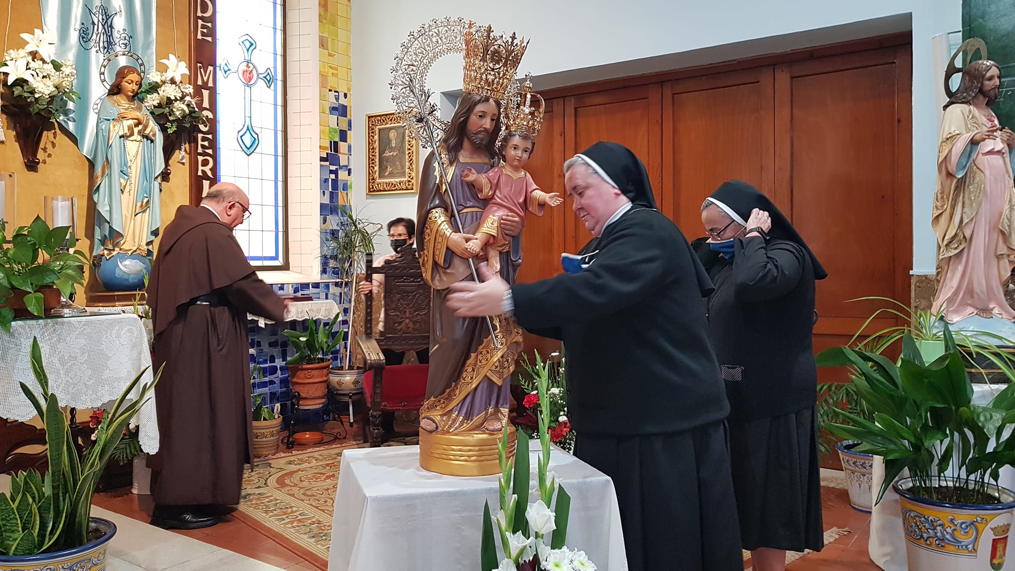 Madre Paloma y Madre Aurora preparan al imagen de San José para la ceremonia de bendición