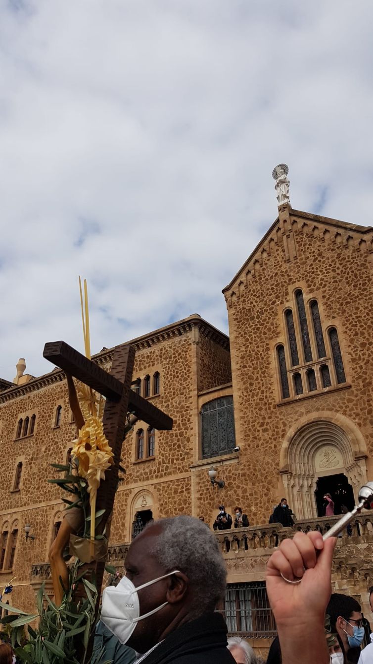 cruz con una palma y hojas de olivo llevado por un deboto. Al fondo se ve el Santuario y la imagen de San José de la Montaña de la fachada.