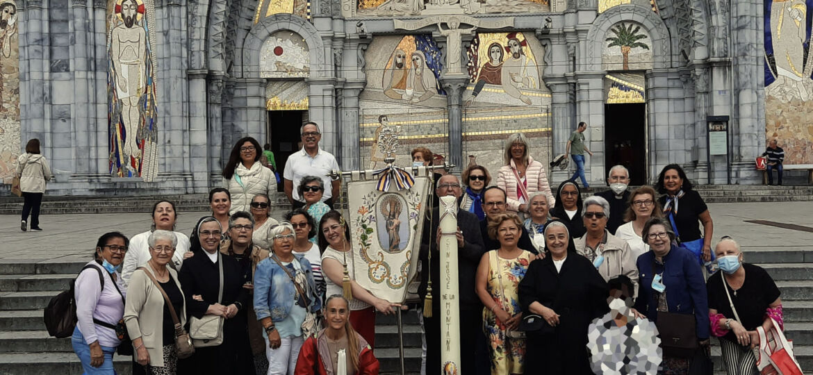grupo con cirio ante el santuario de Lourdes.
