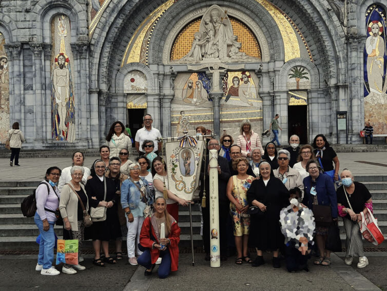 grupo con cirio ante el santuario de Lourdes.