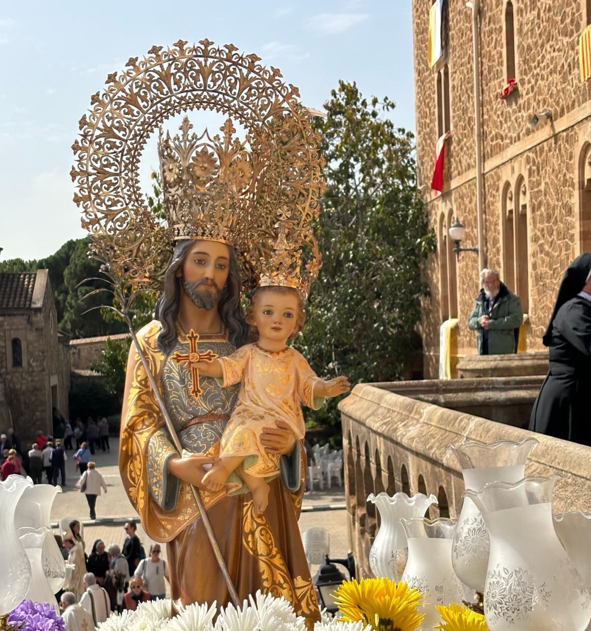 San José de la montaña está subiendo por la escala de piedra del Santuario. En primer plano se ve las flores con los colores de San José: morado, blanco y amarillo.